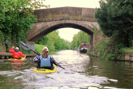 Kayakers paddling down a river towards a bridge
